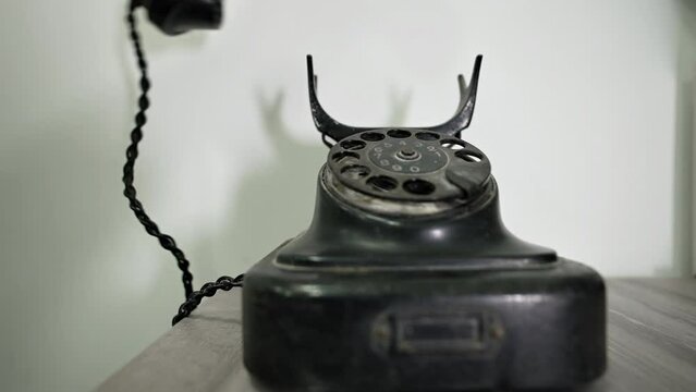 A person dials a number on a vintage telephone. Сalling with black retro phone. Man picks up handset on old phone and turns number plate of device. Close-up Dusty Retro Rotary Landline Phone