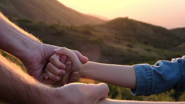 Dad and daughter hold hands against the backdrop of nature. The concept of protection and care for children.