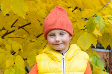 five-year-old girl in background of an autumn tree.