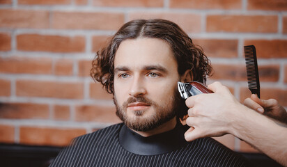 Closeup master hairdresser does hairstyle with scissors comb. Concept Barbershop haircut for man