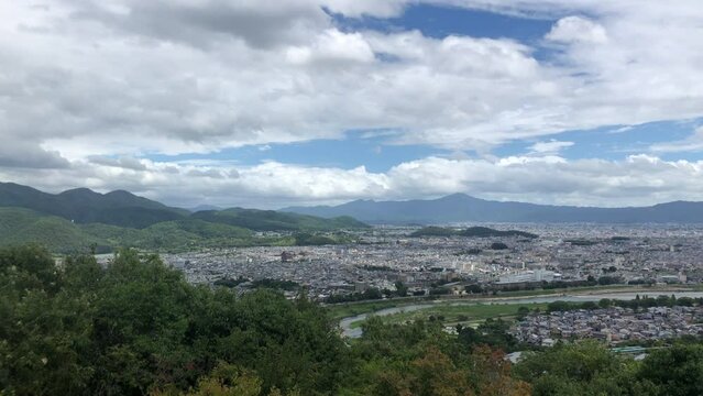 Capture the panoramic view of Arashiyama from the summit of Arashiyama Monkey Park. This footage pans from left to right, showcasing the scenic beauty of the area from the mountaintop.