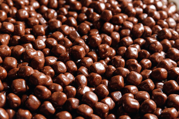 Closeup brown dragee, chocolate covered nuts, sweet candy background