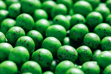 Closeup green dragee, chocolate covered nuts, sweet candy background