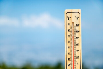 Wooden thermometer with red measuring liquid on a blue sky background 
