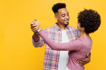 Young romantic happy smiling couple two friends family man woman of African American ethnicity wears purple casual clothes dancing together on party isolated on plain yellow orange background studio.