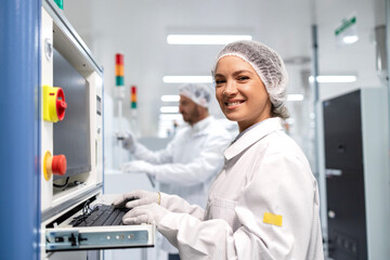 Portrait of female factory worker working in production and assembly line operating computer.