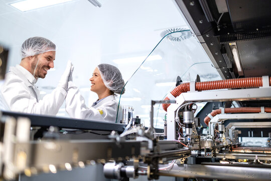 Robotics engineers celebrating success after successfully setting up the production machine in factory.