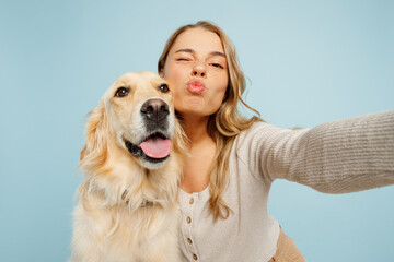 Close up young owner woman with her best friend retriever dog wears casual clothes do selfie shot on mobile cell phone wink isolated on plain pastel light blue background. Take care about pet concept.
