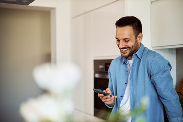 A happy young adult man scrolling through social media on a phone on his work break.