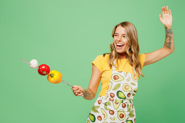 Young fun housewife housekeeper chef cook baker woman wear apron yellow t-shirt hold skewer with...
