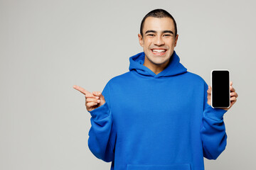 Young surprised middle eastern man wear blue hoody casual clothes hold in hand use blank screen...