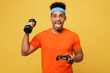 Young fitness trainer instructor sporty man sportsman wears orange t-shirt play pc game hold...