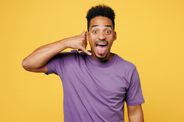 Young excited man of African American ethnicity he wears purple t-shirt casual clothes doing phone...