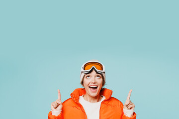 Skier young woman wear warm padded windbreaker jacket hat ski goggles mask point index finger...