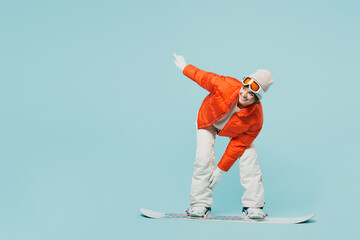 Full body young happy woman wear warm padded windbreaker jacket hat ski goggles mask snowboarding...