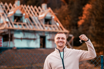 Holding the Future with a New Home Under Construction in the Background. The Man holds the house key.