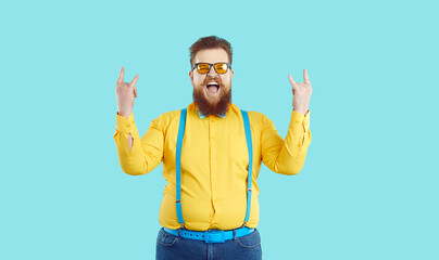 Crazy stylish chubby bearded hipster man rejoices in his success by showing rock and roll symbol....