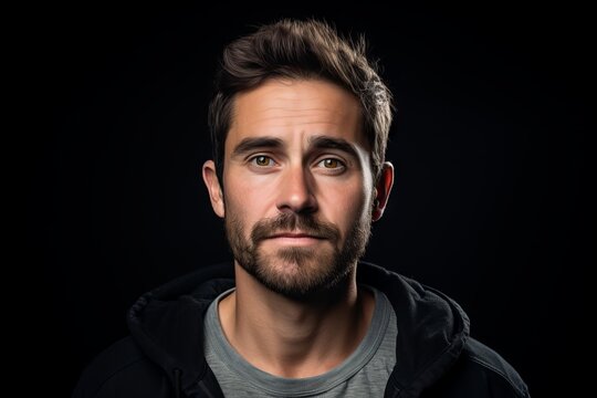 Portrait of a handsome young man with a beard on a black background.