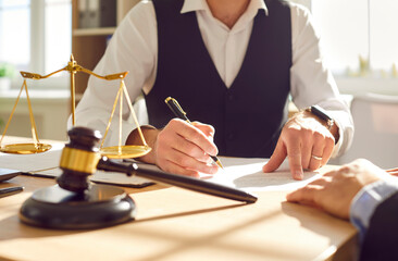 Legal expertise and client service as a lawyer sits across from the client, signing documents in the office. Attorney and client engage in a collaborative act of business and litigation.