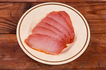 Sliced dry-cured pork loin on saucer on rustic table