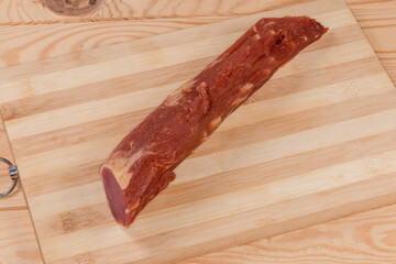 Partly cut dry-cured pork tenderloin on bamboo cutting board