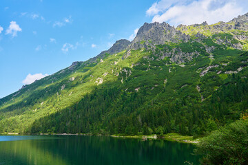 Naklejka na ściany i meble Amazing view on mountains range near beautiful lake at summer day. Tatra National Park in Poland. Panoramic view on Morskie Oko or Sea Eye lake in Five lakes valley