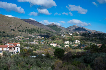 Fototapeta na wymiar Panoramic view over the rough mountains with houses and blue sky around Cannizzaro- Favare, Italy