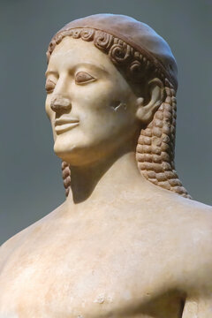 Archaic marble statue of naked young man, kouros, in Athenian museum. Close up portrait. Dec 11, 2018. Athens, Greece