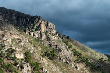 Rough mountain peak with dar rainy clouds in the background around Contrada Rebuttone, Italy