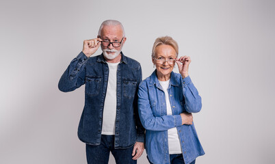 Portrait of smiling senior couple looking out through eyeglasses while standing on white background