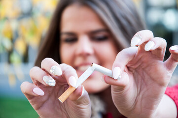 Attractive young happy woman with broken cigarette. No more addiction. Stop smoking concept.