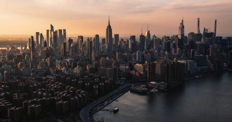 Fototapeta premium New York City Aerial Evening Cityscape with Stunning Manhattan Landmarks, Skyscrapers and Residential Buildings. Long Wide Angle Panoramic Helicopter View of a Popular Travel Destination