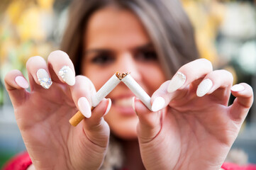 Attractive young happy woman with broken cigarette. No more addiction. Stop smoking concept.