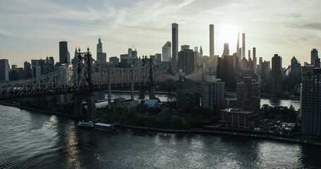 Fototapeta na wymiar New York City Cityscape at Sunset. Aerial Shot from a Helicopter. Modern Skyscraper Buildings Shot Near Ed Koch Queensboro Bridge. Focus on Roosevelt Island and Engineering Details of the Bridge
