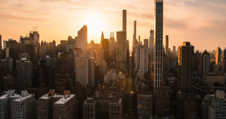 Beautiful Cinematic Aerial Sunset Shot of New York City Skyscrapers and Busy City Streets with Car Traffic. Panoramic Helicopter View of Lower Manhattan Office Buildings