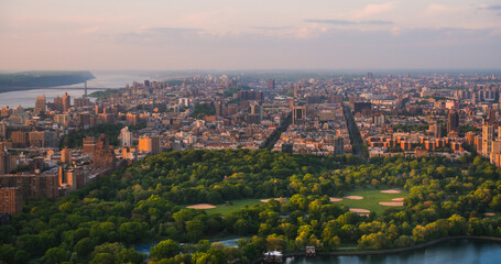 Fototapeta na wymiar New York Cityscape at Sunset. Aerial Shot from a Helicopter. Modern Skyscraper Buildings Around Central Park in Manhattan Island. Focus on Nature, Trees and Lakes in the Park in the City