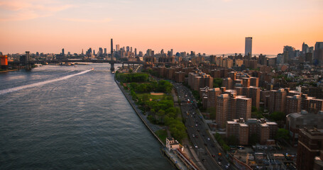 Aerial View of New York City at Sunset. Helicopter Shot of East River and Busy Highway Around Manhattan. Panoramic View with Traffic Around a Big City with Skyscrapers in the Background