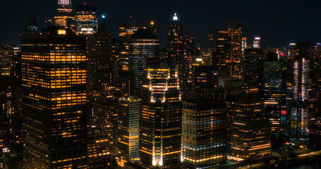 Fototapeta na wymiar Wall Street Office Buildings Lit Up at Night: Scenic Aerial New York City View of Lower Manhattan Architecture. Panoramic Financial District Photo from a Helicopter. Evening Cityscape of NYC