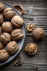 Walnut nuts and kernels in blue plate on old grunge wooden table close up. Food photography