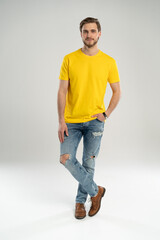 Full length portrait of happy handsome young man in yellow t-shirt isolated on white background.