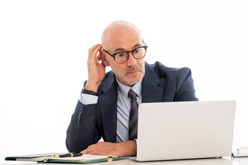 Thinking businessman sitting at desk and using laptops against isolated white background