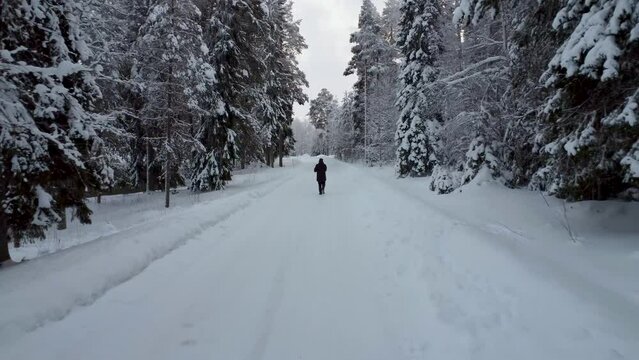 Lone man walking on snow covered road