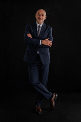 Full length of a mid aged businessman wearing suit and tie against isolated black background