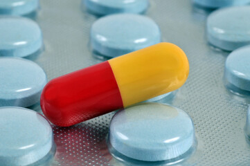 Gélule jaune et rouge en gros plan sur une plaquette de médicaments.