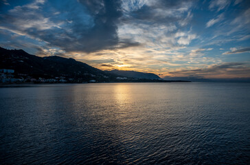 Sunset from the docks over the sea and mountains of the village of Cefalu, Italy