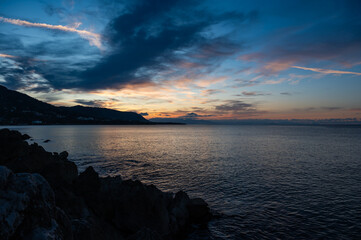 Sunset from the docks over the sea and mountains of the village of Cefalu, Italy