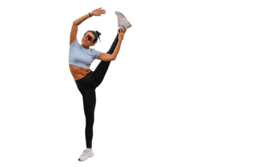Young fit American woman in sportswear rising leg against transparent background training. Tanned flexible girl in sunglasses at exercise . Fitness, flexibility