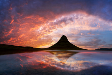 Incredible sunset over Kirkjufell mountain reflected in the clear waters of a mountain lake in...