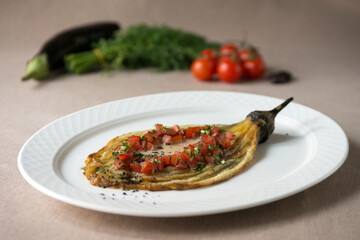 Eggplant baked with tomato and parsley on a white plate