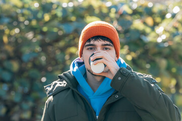 young man bundled up in winter drinking